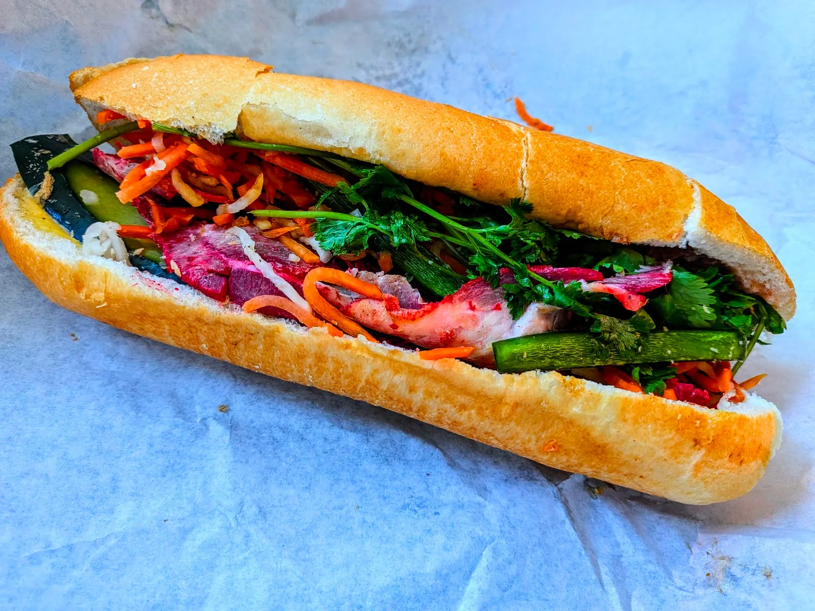 A Vinh Xuong banh mi on a fresh-baked baguette with pickled vegetables and herbs